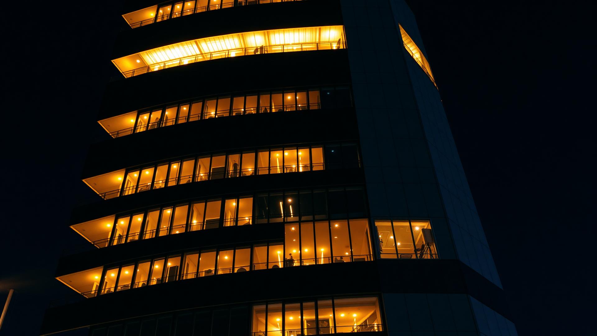 Fachada de condomínio moderno com iluminação e segurança eletrônica à noite